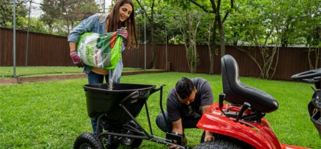 woman adding grass seed to a tiller attachment on a riding lawn mower