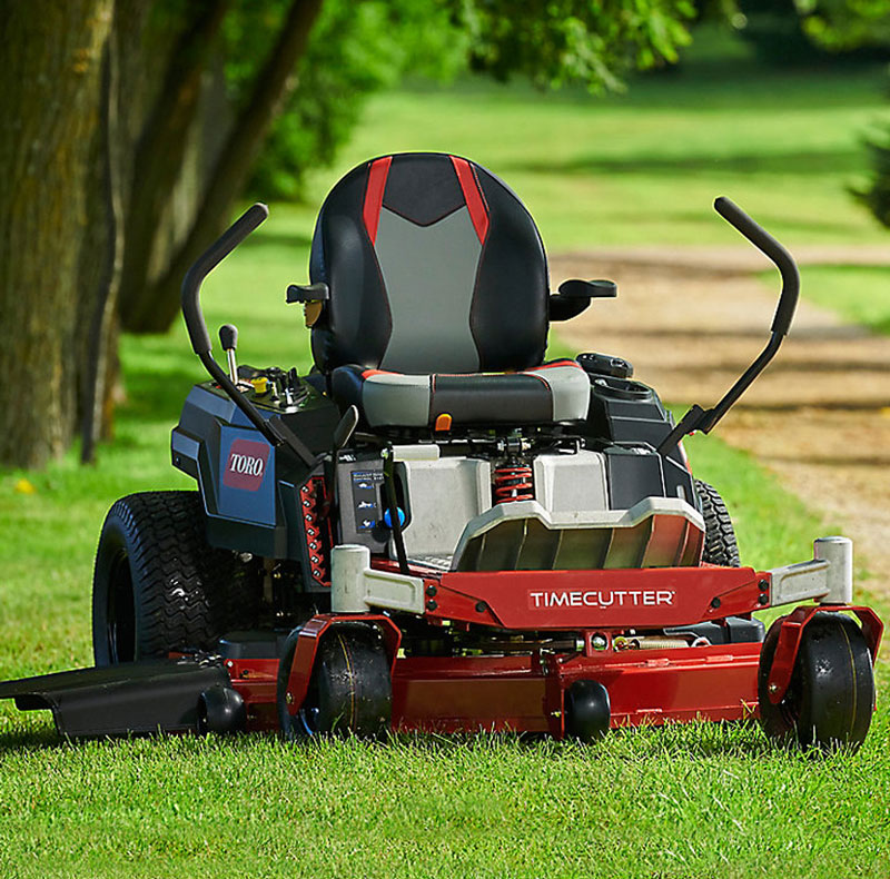 Toro red and black zero-turn riding mower parked on grass next to dirt path