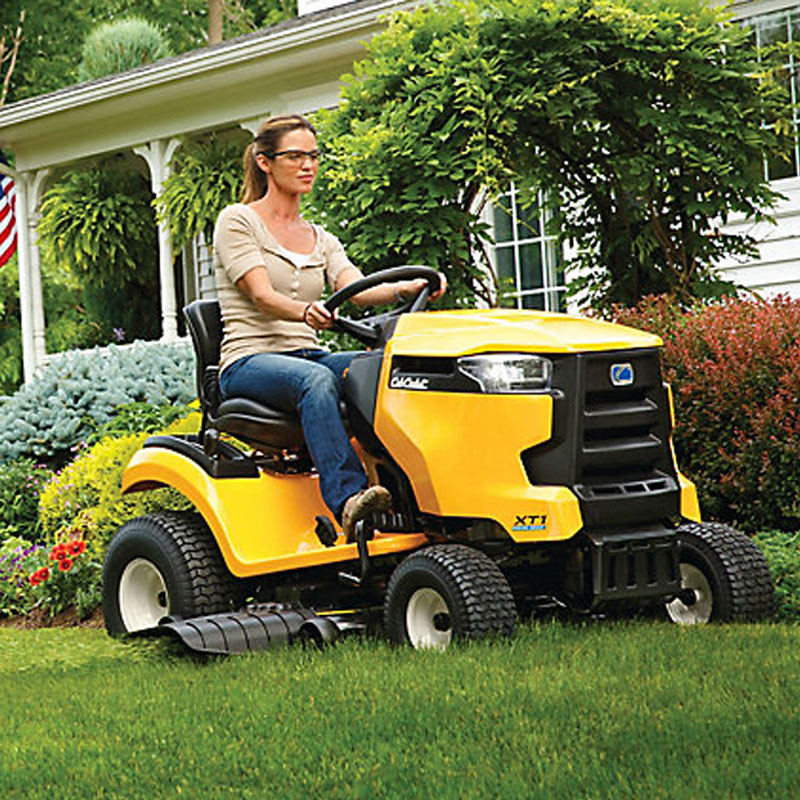 Woman mowing grass in front yard of home with Cub Cadet yellow riding mower 