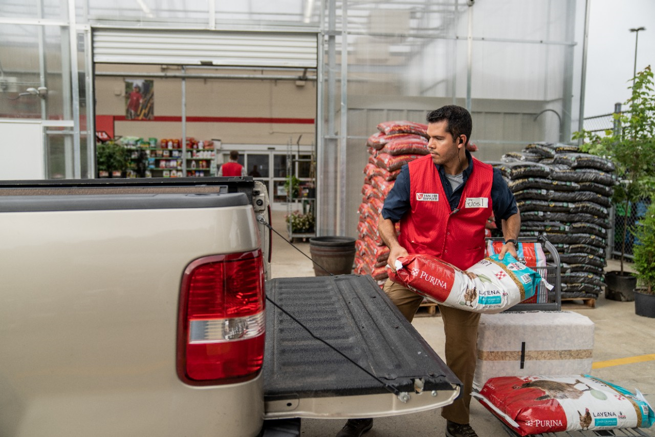 Image of a TSC team member loading poultry feed into a truck.