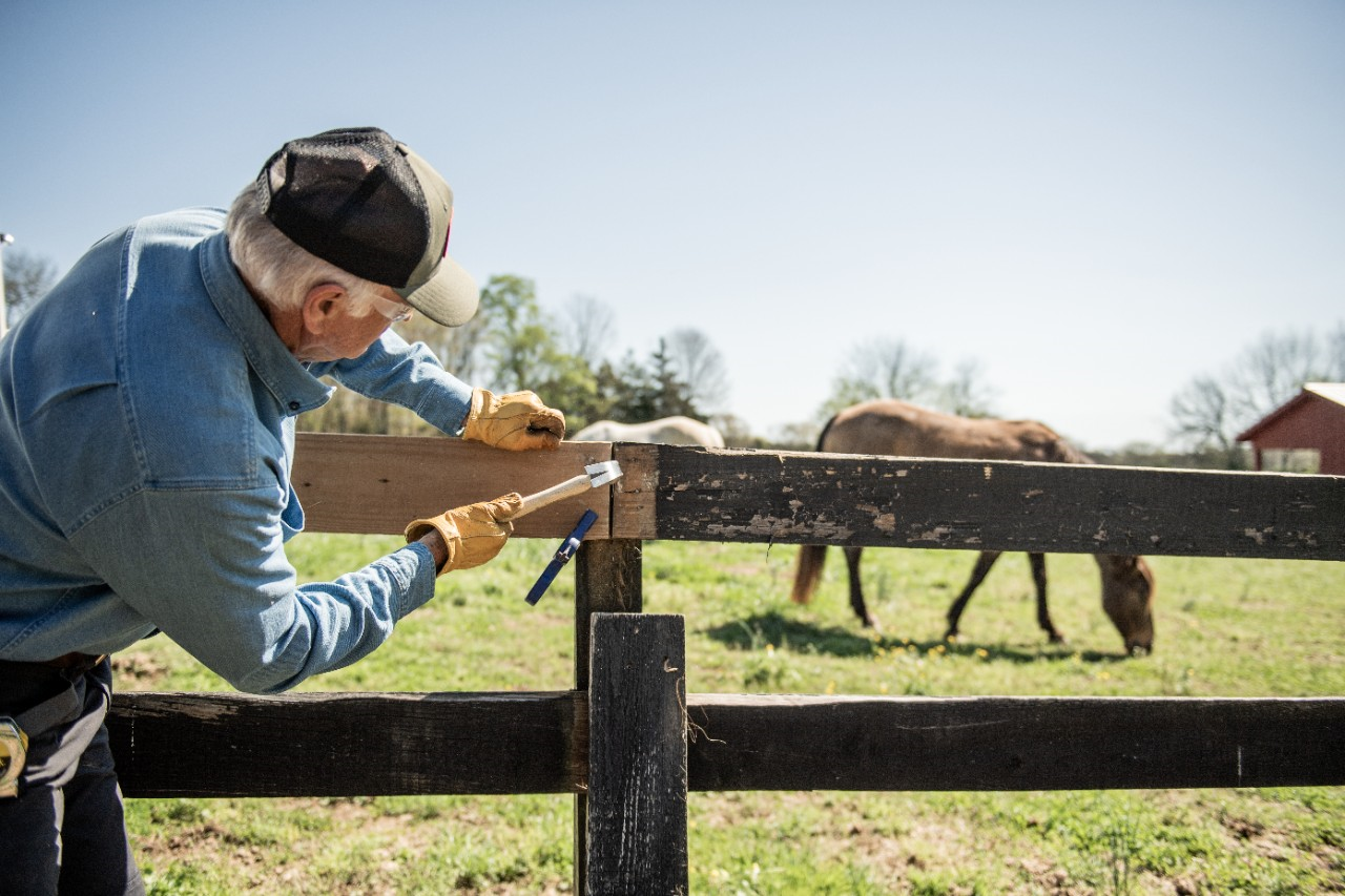 Image of a person repairing a split rail fence.